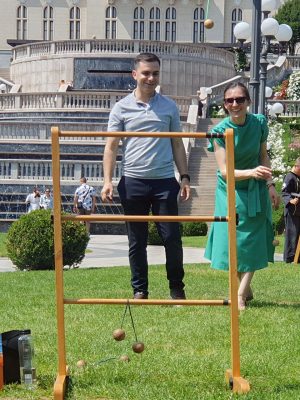 Ea și el zâmbitori îmbrăcați elegant se joacă aruncarea bilelor în centrul orașului Iași