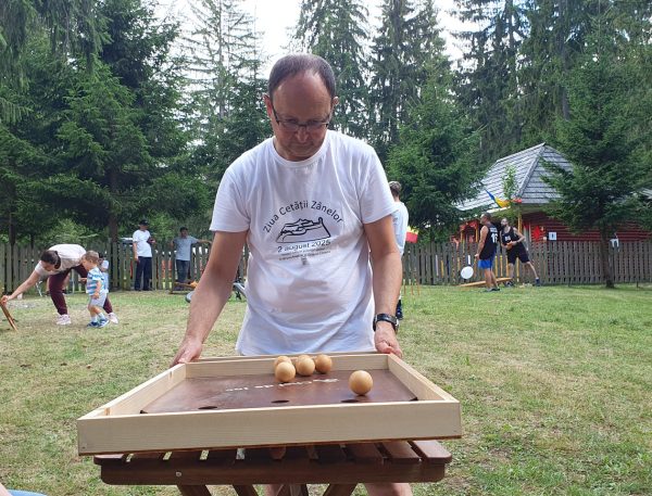 Jucător echilibrează tabla pentru a poziționa bilele în jocul Echilibile