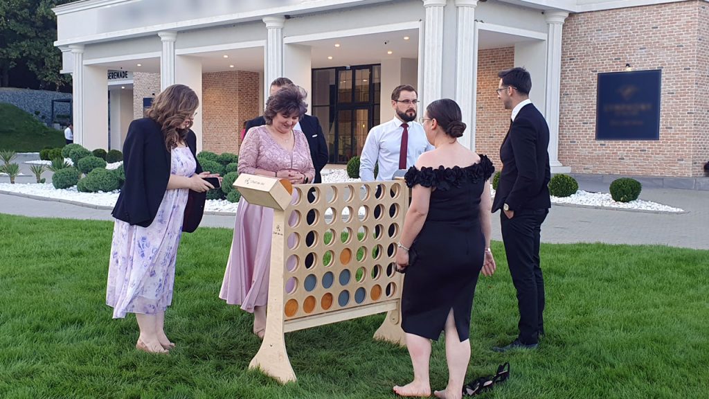 Grup de nuntași în jurul jocului Connect 4 gigant din lemn la nuntă