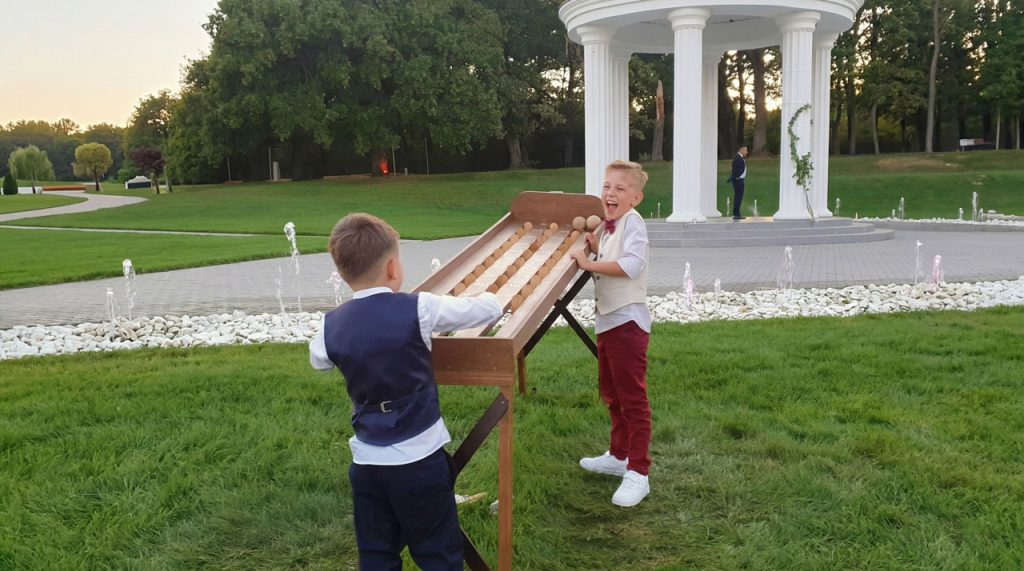 Doi băieți îmbrăcați de nuntă jucând Click Ball în grădină