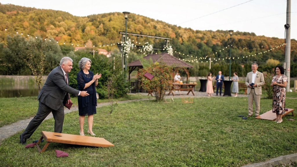 Nuntași eleganti jucând Cornhole în grădină la nuntă