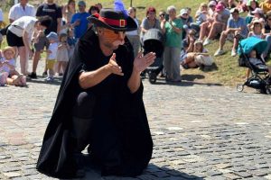 Actor în costum de Motanul Încălțat în spectacol de stradă, cu public numeros în fundal, festival Brașov