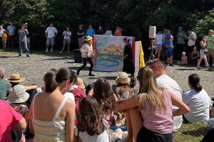 Spectacol de teatru de stradă cu actori și decor pictat, înconjurați de public numeros la festival în aer liber