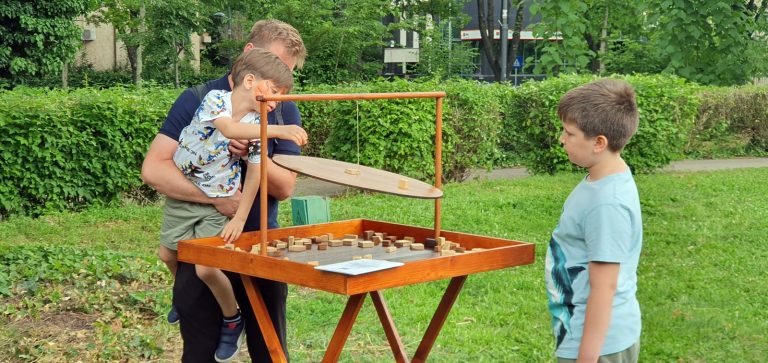 Tată și copil jucând jocul de echilibru Contrabalans, în grădina TVR de Ziua Copilului