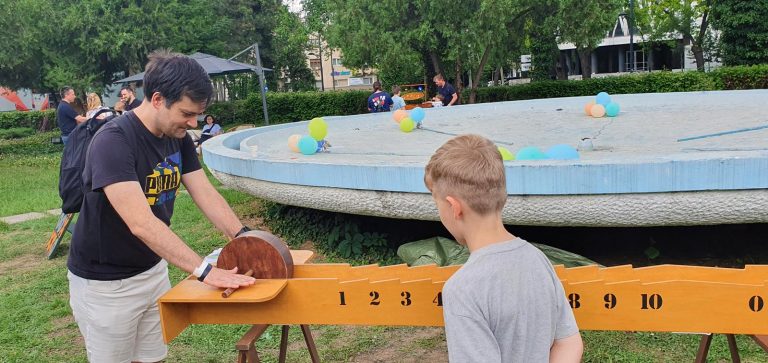 Adult și copil jucând Roata Morii, de Ziua Copilului în grădina Televiziunii Române